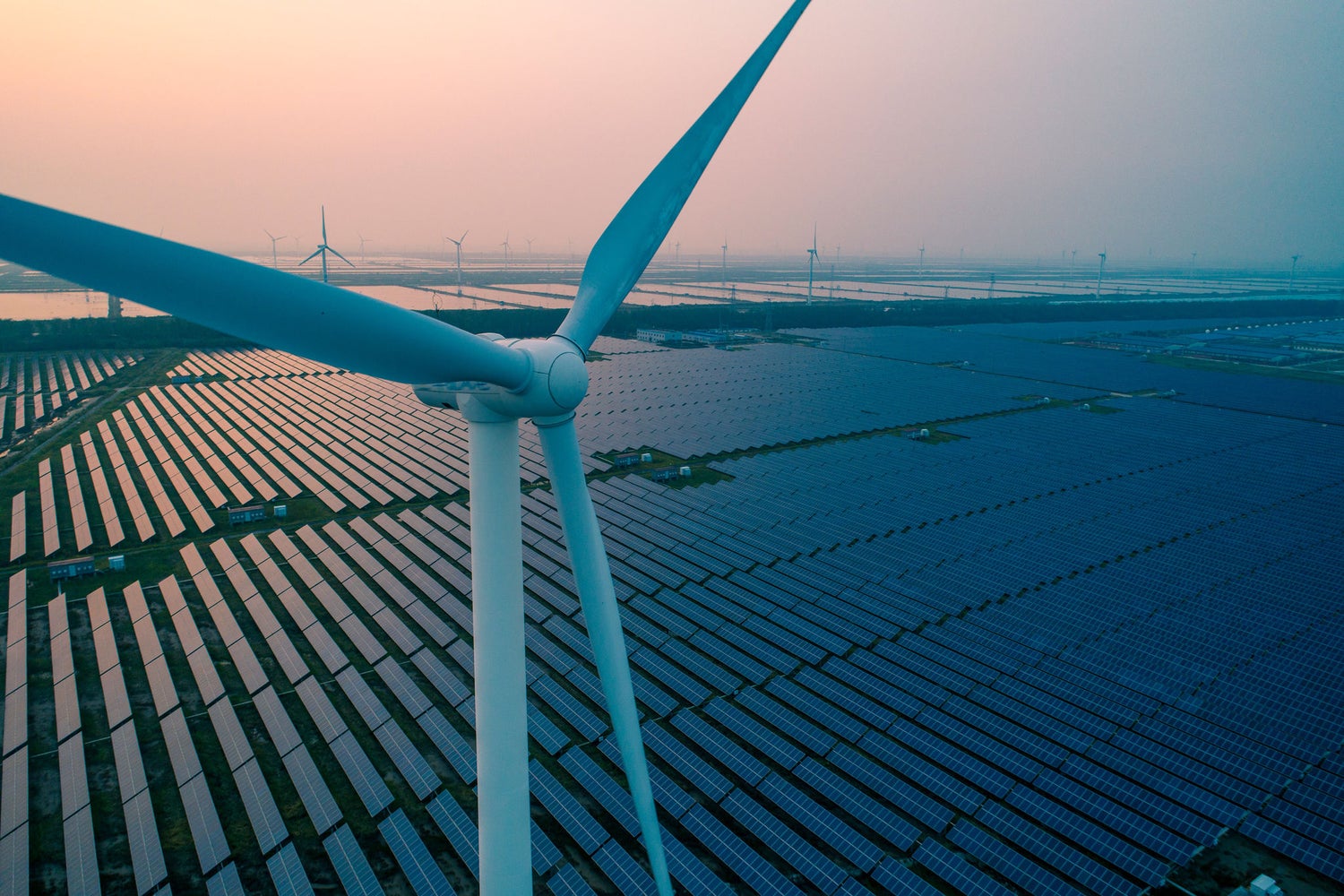 A wind turbine in front of solar panels